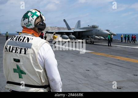 Aviation Structural Mechanic 1. Class Thomas Trosper, aus Georgetown, Illinois, angeschlossen an das ÒRaginÕ BullsÓ of Strike Fighter Squadron (VFA) 37, beobachtet ein F/A-18F Super Hornet, das sich auf dem Cockpit des erstklassigen Flugzeugträgers USS Gerald R. Ford (CVN 78) auf den Start vorbereitet, 28. März 2023. Ford ist im Atlantik dabei, seine Composite Training Unit Exercise (COMPTUEX) durchzuführen, eine intensive, mehrwöchige Übung, die darauf abzielt, eine Trägerstreikgruppe als zusammenhängende, multimissionale Kampftruppe vollständig zu integrieren und ihre Fähigkeit zur Durchführung nachhaltiger Kampfoperationen zu testen Stockfoto