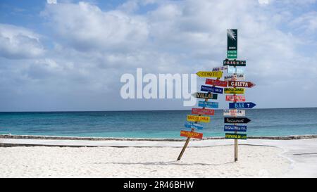 Ein hölzerner Schild steht an einem Strand mit einem malerischen Blick auf das Meer im Hintergrund Stockfoto