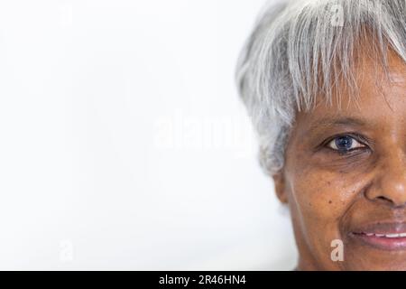 Unverfälschtes Porträt eines halben Gesichts einer glücklichen leitenden, birassischen Patientin, die lächelt, mit Kopierraum Stockfoto