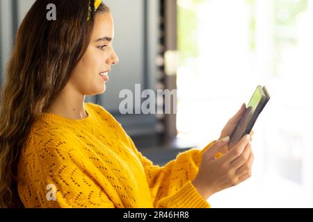 Seitenansicht einer lächelnden, birassischen, jungen, schönen Frau, die ein digitales Tablet zu Hause verwendet, Kopierbereich Stockfoto