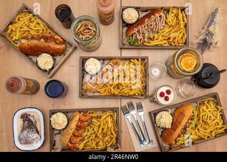 Auswahl an leckeren Hot-Dog-Gerichten, garniert mit pommes frites, Salaten und Getränken Stockfoto