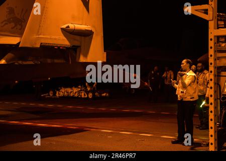 Aviation Boatswain's Mate 2. Class Jayla Delgado, dem erstklassigen Flugzeugträger USS Gerald R. Fords (CVN 78) Air Department zugewiesen, leitet eine F/A-18F Super Hornet, die an die „Blacklions“ der Streikkampfgeschwader (VFA) 213 angeschlossen ist, in die Hangarbucht des Schiffs, 24. März 2023. Ford ist im Atlantik dabei, seine Composite Training Unit Exercise (COMPTUEX) durchzuführen, eine intensive, mehrwöchige Übung, die darauf abzielt, eine Trägerstreikgruppe als zusammenhängende, multimissionale Kampftruppe vollständig zu integrieren und ihre Fähigkeit zur Durchführung nachhaltiger Kampfoperationen vom Meer aus zu testen. Als die Stockfoto