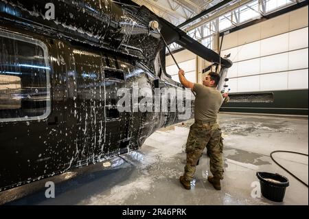 USA Army SPC. James Payne, UH-60 Helikopter-Reparateur mit dem 1. Assault Helicopter Bataillon, 150. Aviation Regiment, wäscht einen UH-60m Black Hawk auf der Joint Base McGuire-Dix-Lakehurst, New Jersey, 10. April 2023. Die Black Hawks werden regelmäßig gewaschen, um Korrosion und Schäden zu verhindern und die Einsatzbereitschaft aufrechtzuerhalten. Stockfoto