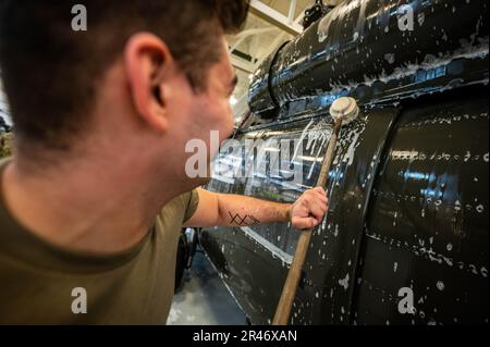 USA Army SPC. James Payne, UH-60 Helikopter-Reparateur mit dem 1. Assault Helicopter Bataillon, 150. Aviation Regiment, wäscht einen UH-60m Black Hawk auf der Joint Base McGuire-Dix-Lakehurst, New Jersey, 10. April 2023. Die Black Hawks werden regelmäßig gewaschen, um Korrosion und Schäden zu verhindern und die Einsatzbereitschaft aufrechtzuerhalten. Stockfoto