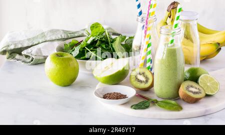 Ein grüner Smoothie, umgeben von Zutaten, aus denen er hergestellt wird. Stockfoto