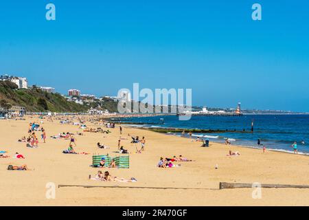 Bournemouth, Großbritannien - Mai 26. 2023: Sonnenanbeter am Alum Chine Beach mit Bournemouth Pier im Hintergrund. Stockfoto