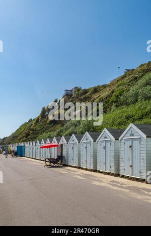 Bournemouth, Großbritannien - Mai 26. 2023: Ein Mann, der sich vor seiner Strandhütte an der West Undercliff Promenade entspannt. Stockfoto