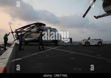 Südchinesisches Meer (11. März 2023) – USA Marines, die der Marine Medium Tiltrotor Squadron (VMM) 362 (rein.), 13. Marine Expeditionary Unit, und Matrosen, die der Amphibien-Transportanlage USS John P. Murtha (LPD 26) zugewiesen sind, verlegen einen CH-53E Super Hallion an Bord des John P. Murtha, März 11. Das Navy-Marine-Corps-Team, das sowohl für schnelle Reaktionen als auch für nachhaltige Einsätze weltweit in der Lage ist, bleibt Amerikas hartnäckigstes und vielseitigstes militärisches Instrument durch ständige Ausbildung und Wartung in der Luftfahrt. Die 13. MEU wird von der Makin Island Amphibious Ready Group gestartet, die sich aus dem Verstärker zusammensetzt Stockfoto