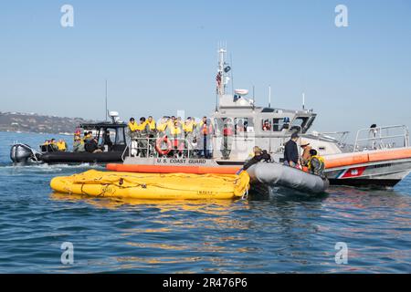 230119-N-LR048-1088 SAN DIEGO (19. Januar 2023) – Marinesoldaten, die dem Helicopter Sea Combat Squadron (HSC) 3 (Front) zugeteilt sind, stellen ein 46-Mann-Rettungsfloß auf, als Besatzungsmitglieder, die dem Air Force 445. Airlift Wing zugeteilt sind, bereiten sich auf das Aussteigen aus den USA vor Schiff der Küstenwache (USCG) (Back), dem Küstenwachesektor San Diego zugeteilt während eines Massenunfalls bei der Bergung des Seemanns vor der Küste Südkaliforniens, Januar 19. Während der Evolution beaufsichtigte der Leiter des Such- und Rettungsmodells des HSC-3-Marineeinsatzes die Such- und Rettungsübung mit HSC-8, HSC-23, Küstenwachesektor San Diego und Crewmemb Stockfoto