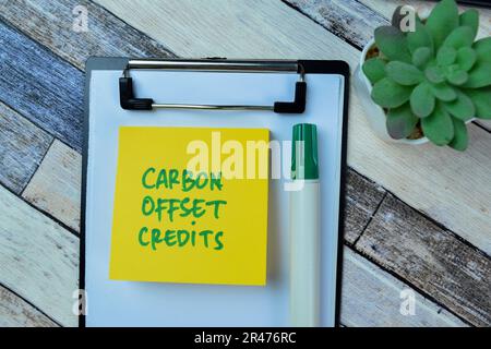 Konzept von Carbon Offset Credits zum Schreiben auf Haftnotizen, die auf einem Holztisch isoliert sind. Stockfoto