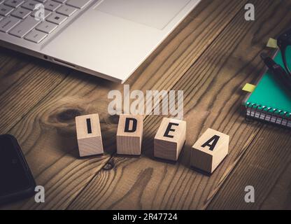 Laptop, Notebook, Stift und Brille, Handy, Ideenwort mit Holzwürfeln auf einem alten Holztisch geschrieben. Kreativität und Geschäftskonzept. Stockfoto