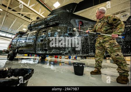 USA Army Staff Sergeant Daniel Montgomery, UH-60 Helikopter-Reparateur mit dem 1. Assault Helicopter Bataillon, 150. Aviation Regiment, wäscht einen UH-60m Black Hawk auf der Joint Base McGuire-Dix-Lakehurst, New Jersey, 10. April 2023. Die Black Hawks werden regelmäßig gewaschen, um Korrosion und Schäden zu verhindern und die Einsatzbereitschaft aufrechtzuerhalten. Stockfoto