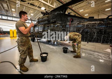 USA Army Staff Sergeant Daniel Montgomery, Right, und SPC. James Payne, beide UH-60 Helikopter-Reparateure mit dem 1. Assault Helicopter Battalion, 150. Aviation Regiment, waschen einen UH-60m Black Hawk auf der Joint Base McGuire-Dix-Lakehurst, New Jersey, 10. April 2023. Die Black Hawks werden regelmäßig gewaschen, um Korrosion und Schäden zu verhindern und die Einsatzbereitschaft aufrechtzuerhalten. Stockfoto