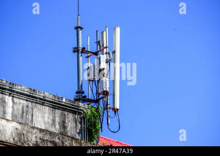Drei Mobilfunkmasten auf einem Gebäude vor einem blauen Himmel Stockfoto