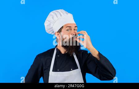 Kochen Sie mit Köchen-Hut mit einer Geschmacksnote. Ein professioneller Koch zeigt ein Schild für Delicious. Männlicher Koch in Uniform mit perfektem Zeichen. Bärtiger Koch, Koch Stockfoto