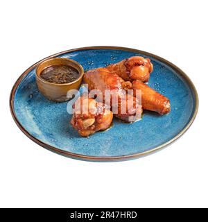 Mit Speck umwickelte gegrillte Hähnchenflügel auf dem Teller. Leckerer Snack mit Hähnchenfleisch, saurer, salziger und würziger Sauce. Stockfoto