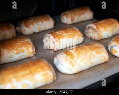 Frisch gebackene Brötchen auf Backpapier, selektiver Fokus. Goldbraune Brötchen im Ofen zubereitet. Hausgemachtes Essen Stockfoto