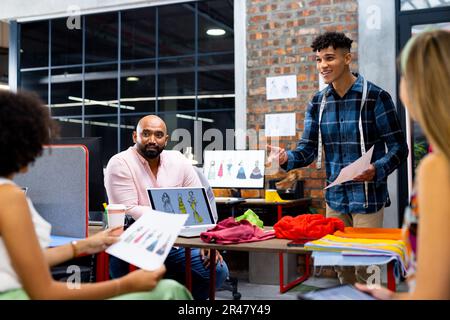 Fröhliche, vielfältige Modedesigner diskutieren Modeprojekte bei einem Meeting in einem Kreativbüro, unverändert Stockfoto