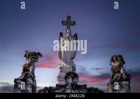 Eine Gruppe von Statuen hoch oben auf einem felsigen Felsvorsprung, Silhouette vor einem dramatischen Himmel Stockfoto