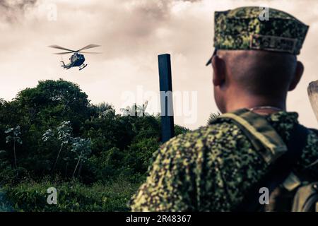 Ein kolumbianischer Marine schaut auf eine Armada Nacional de la Republica de Colombia (Kolumbianische Marine) Bell UH-1N Twin Huey auf kolumbianischem Marinestützpunkt Turbo, Turbo, Kolumbien, 24. Januar 2023. USA Marinekorps, Lieutenant General David Bellon, Kommandeur der USA Marine Corps Forces, Süd und USA Die Reserve der Marinekorps, seine Mitarbeiter und die Führer des 4. Assault-Amphibienbataillons reisten nach Kolumbien, um sich mit der Führung des Infantería de Marina Colombiana (Kolumbianisches Marinekorps) zu treffen, um die Partnerschaft zwischen den beiden Navies und dem Marinekorps weiter zu stärken. Stockfoto