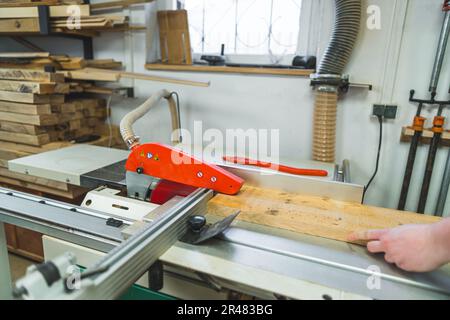 Tischler gleitende Holzbohle unter elektrischer Tischsäge im Holzbearbeitungsstudio. Hochwertiges Foto Stockfoto