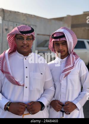 Eine vertikale Nahaufnahme von zwei jungen arabischen Männern in traditionellen Outfits, die posieren Stockfoto