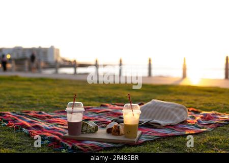 Nahaufnahme der Decke mit Getränken und Speisen auf der Promenade am Meer bei Sonnenuntergang, mit Kopierbereich Stockfoto