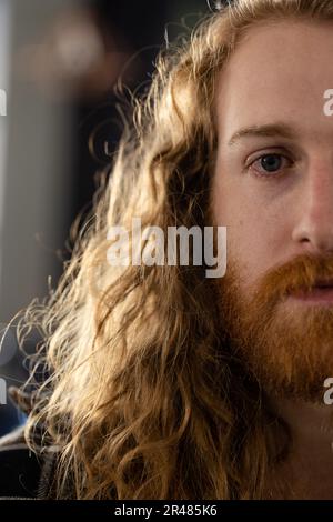 Halbes Porträt eines männlichen Kaukasiers mit langen lockigen roten Haaren und Bart im Friseursalon Stockfoto