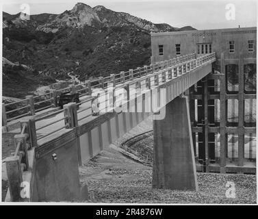 Blick auf den Fluss von der Oberseite des Staudamms, der zeigt, dass die Servicebrücke und der Auslasssteuerturm fertig gestellt sind. Lage, Prado... Stockfoto