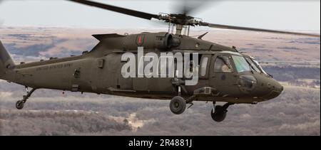 Ein UH-60 Black Hawk Helikopter, der der 1. Kampfluftfahrtbrigade, 1. Infanteriedivision, zugeteilt wurde, fährt über 1. Inf. Div Hauptquartier in Fort Riley, Kansas, 7. März 2023. Soldaten führten eine rein weibliche Überführung durch und besuchten das Amelia Earhart Museum, um die Leistungen von Frauen in der Luftfahrt zu feiern. Stockfoto