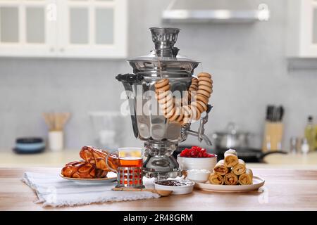 Traditioneller russischer Samovar und Leckereien auf Holztisch in der Küche Stockfoto