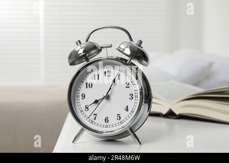 Silberner Wecker auf weißem Nachttisch im Schlafzimmer Stockfoto