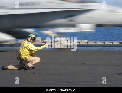 US Navy Flugdeck-Handler signalisiert Start einer F-A-18 Hornet vom Flugdeck Stockfoto