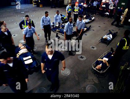 MEDIZINISCHES Personal DER US Navy an Bord und Träger von Bahren betreuen simulierte Verletzte während einer Massentrainingübung an Bord des Amphibienschiffs USS Kearsarge (LHD 3) Stockfoto