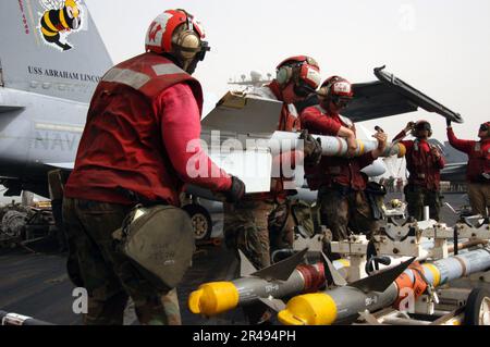 US Navy Aviation Ordnancemen laden eine AIM-9 Sidewinder Luft-Luft-Rakete von einer F-A-18C an Bord der USS Abraham Lincoln (CVN 72) herunter Stockfoto