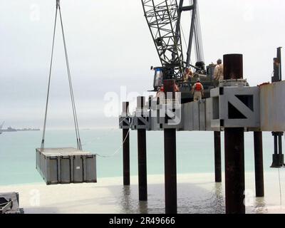 US Navy USA Marineseabees, die Amphibien-Battalionen (ACB) zugeteilt sind. Eins und zwei heben den nächsten Straßenabschnitt an, der für den Bau der erhöhten Causeway System-Modular (ELCAS (M))-Struktur verwendet wird Stockfoto