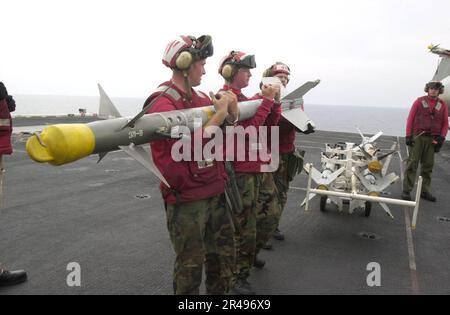 US Navy Aviation Ordnancemen heben eine AIM-9M Sidewinder Luft-Luft-Rakete hoch, um sie auf eine F-A-18 Hornet an Bord der USS Nimitz (CVN 68) hochzuladen. Stockfoto