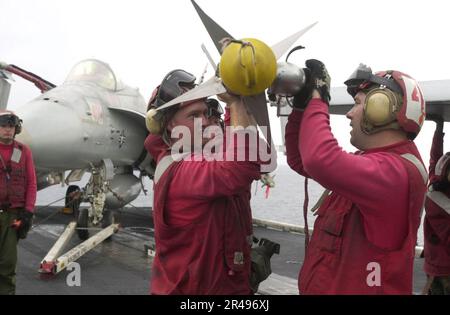 US Navy Aviation Ordnancemen heben eine AIM-9M Sidewinder Luft-Luft-Rakete hoch, um sie auf eine F-A-18 Hornet an Bord der USS Nimitz (CVN 68) hochzuladen. Stockfoto