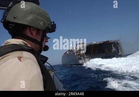 Mitglied des US Navy Special Boat Team fungiert als Sicherheitsbeobachter hinter Joint Venture High Speed Vessel Experimental One (HSV X1) während einer Schulung zur Suche und Beschlagnahme von Schiffen an Bord Stockfoto