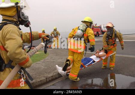 US Navy Feuerwehrleute vom Kommandanten, Naval Forces, Japan Regional Fire Department sind als erste vor Ort, um simulierten Verletzten während einer Hubschrauberabsturzübung zu helfen Stockfoto