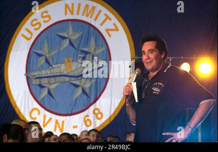 US Navy Actor-Entertainer Wayne Newton tritt während einer United Services Organization (USO) Show an Bord der USS Nimitz auf der Bühne auf (CVN 68) Stockfoto