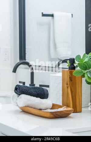 Auf der Ablagefläche eines modernen, weiß gefliesten Badezimmers befindet sich ein Satz Badetücher Stockfoto