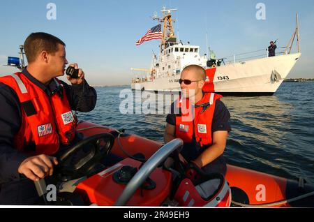 MATE 1. Class der US Navy Boatswain spricht per Funk mit den USA Küstenwache Cutter Bainbridge Island auf Patrouille im Hafen von New York Stockfoto