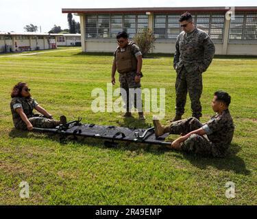 USA Navy Petty Officer 1. Klasse Marvin Gambito, ein Sanitäter des Krankenhauses, Left, weist die USA an Marines Sgt. Samuel Berkheimer, Left Center, A Fire Support Marine, CPL Robert MendozaLopez Jr., Right Center, Und Lance CPL Guadalupe Garcia, rechts, Verwaltungsspezialisten mit 3. Marine Expeditionary Brigade, III Marine Expeditionary Force und Task Force 76/3, wie man einen Wurf während eines taktischen Kampfnotfallbetreuungskurses an Bord von Camp Courtney, Okinawa, Japan, aufstellt, 6. April 2023. TCCC wurde von den USA entwickelt Department of Defense Defense Health Agency (DHA) gemeinsames Trauma-System, um Evidenz zu lehren Stockfoto