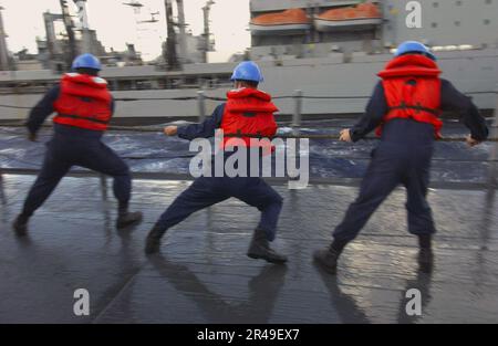 US Navy-Matrosen an Bord des geführten Raketenkreuzers USS Philippine Sea (CG 58) hüpfen auf einer Leine während einer Wiederauffüllung auf See mit der USNS Kanawha (T-AO 196) auf dem Weg im Atlantischen Ozean herum Stockfoto