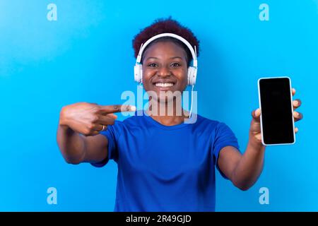 Ein Porträt einer jungen, fröhlichen schwarzen Frau, die Musik mit Kopfhörern hört Stockfoto