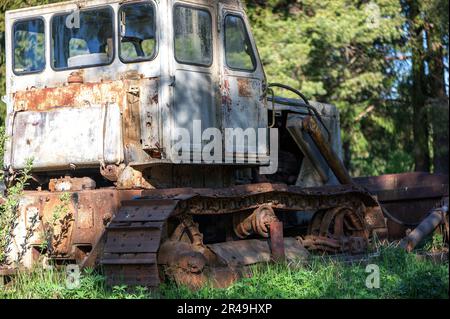 Ein alter Bulldozer mit rostigem Äußeren, in einer grasbedeckten Landschaft geparkt Stockfoto