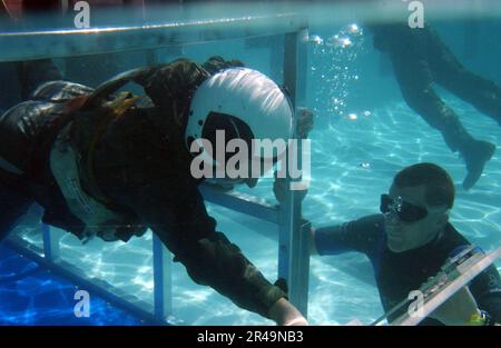 US Navy Ein Student, der am Aviation Water Survival Kurs teilnimmt, schwimmt durch eine Kammer, die das Innere eines Flugzeugs simuliert Stockfoto