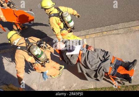 US Navy Fire Fighters vom Commander, USA Marine Forces Japan Regional Fire Department, helfen Sie bei der Evakuierung simulierter Patienten in einer Massenübung für Verletzte Stockfoto
