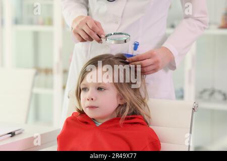 Der Kinderarzt sucht Läuse auf dem Kopf eines kleinen Mädchens im Stuhl Stockfoto